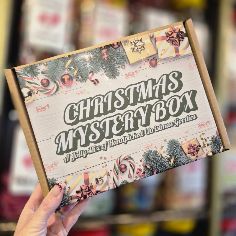 Christmas mystery box with festive design held by a hand against a blurred background