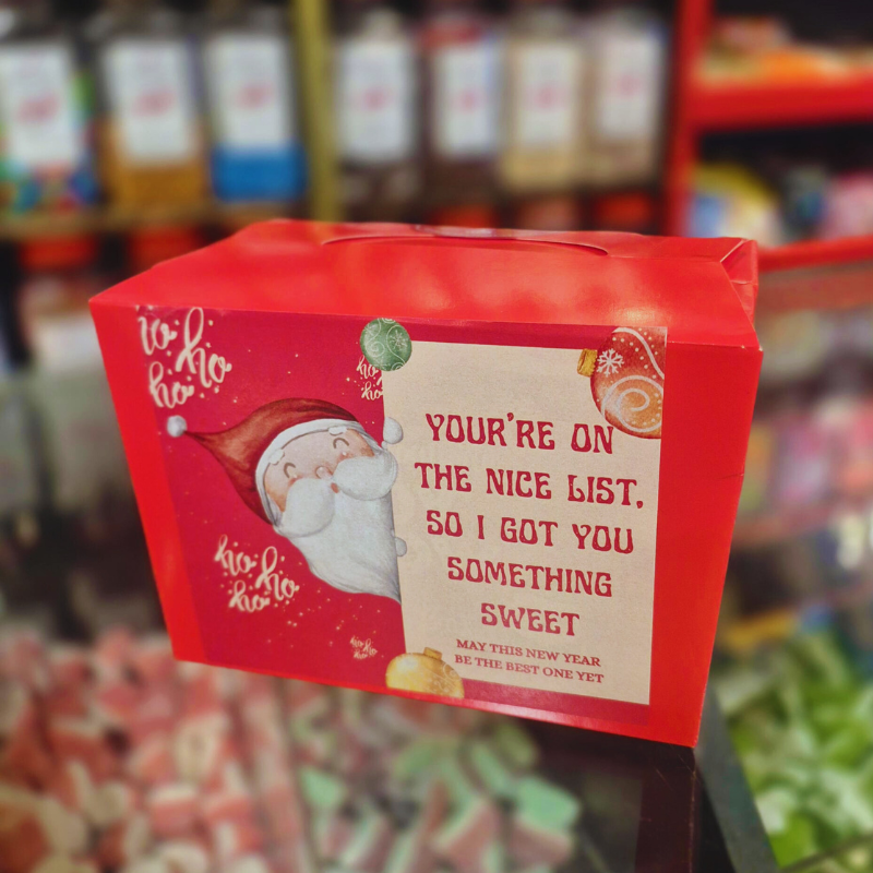 Red gift box with Santa Claus illustration and text in a store setting